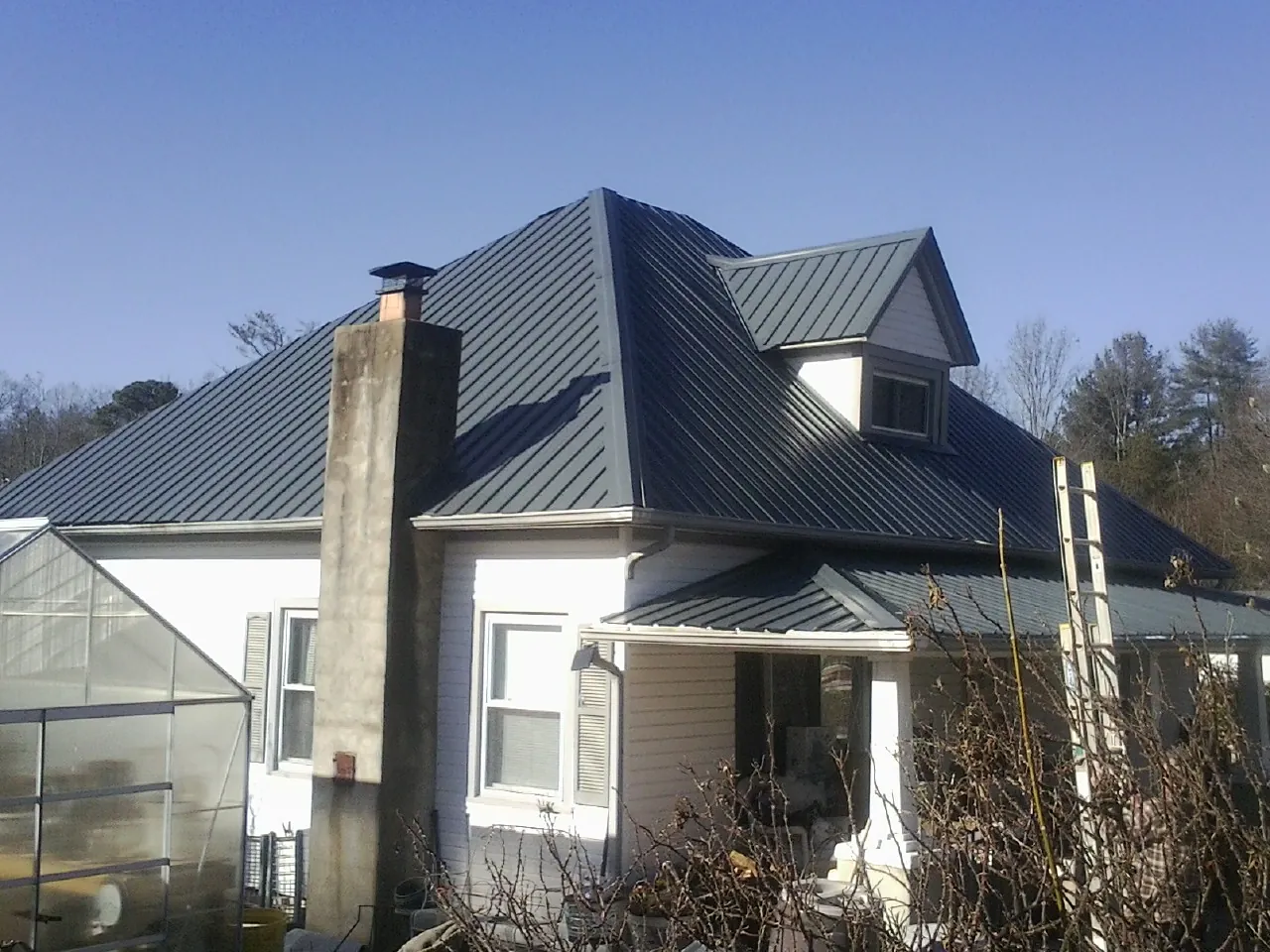 Dark blue standing seam metal roof on a white farmhouse with dormer — Slate & Tile Roof Repair by Roofing Brothers in Auburn